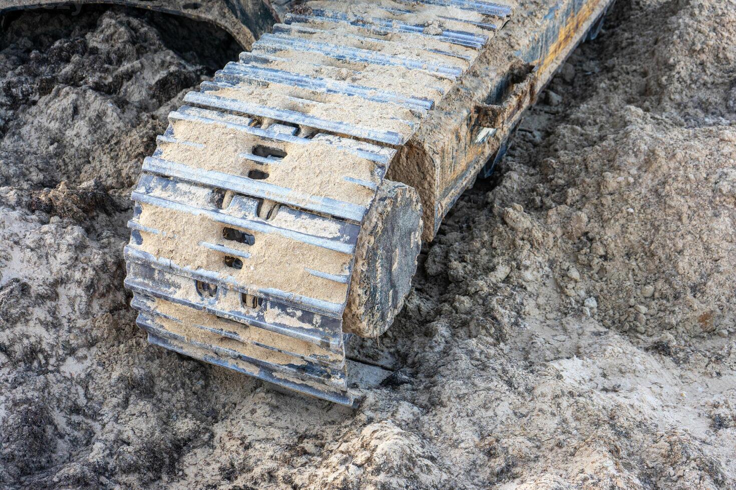 Close-up of excavator caterpillars on rough terrain, showcasing detailed treads and dirt accumulation. Ideal for construction and machinery themes. photo