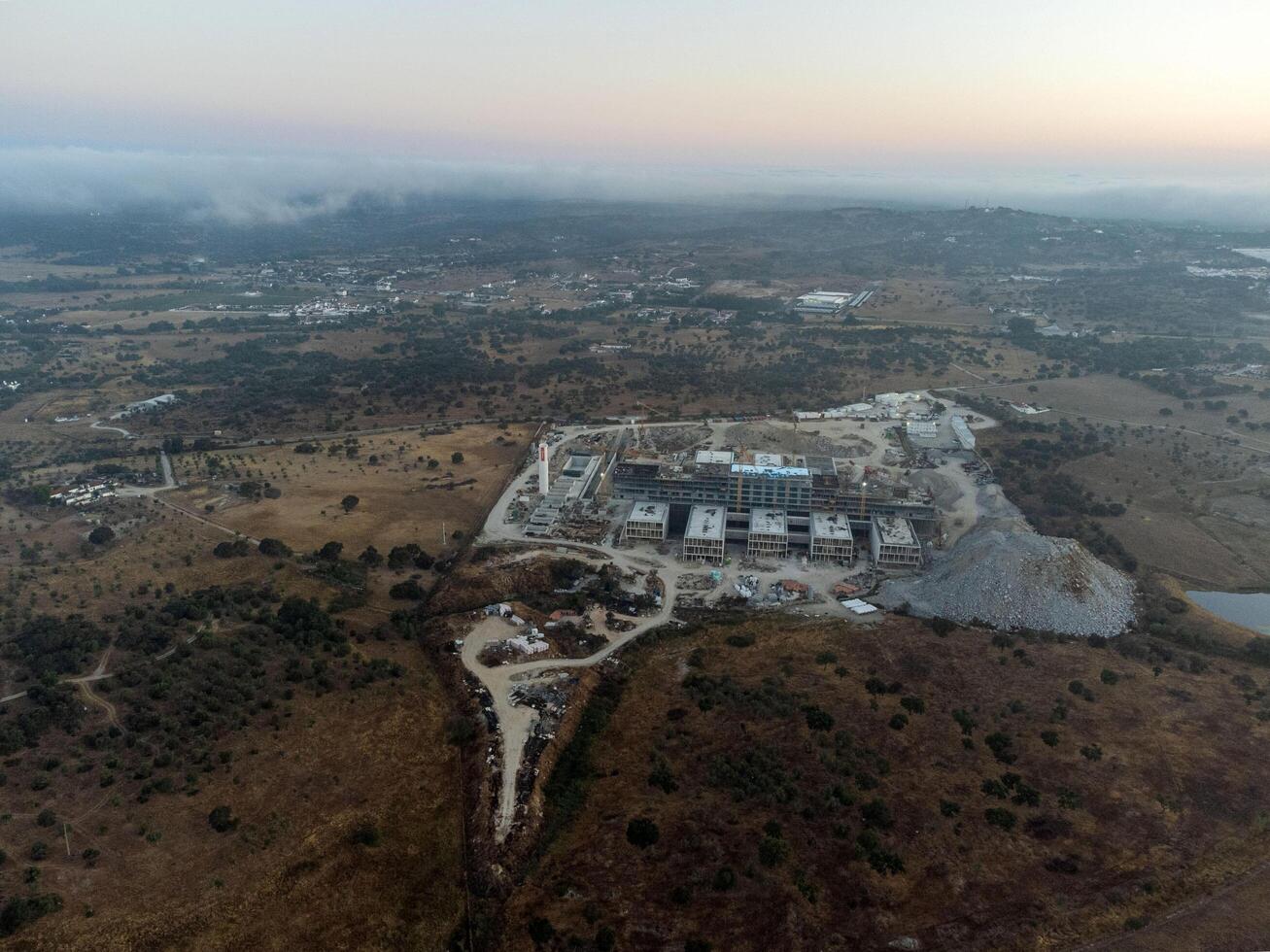 Evora, Portugal. August 8, 2024. Aerial view of the construction site of the new Evora District Hospital, showcasing cranes, scaffolding, and the partially completed modern structure. photo