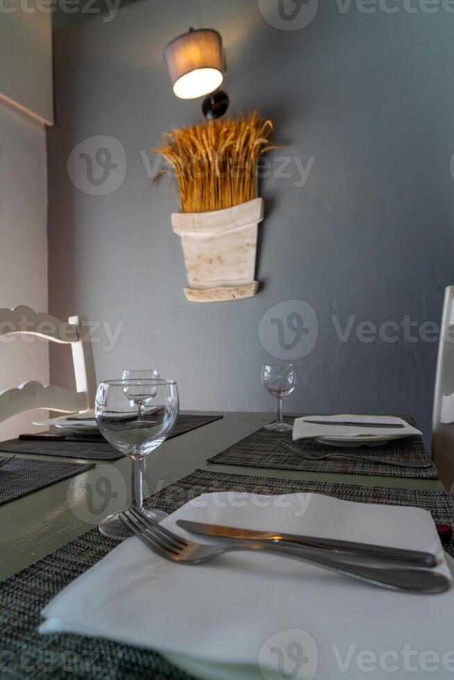 A restaurant table set in natural light, with simple dinnerware, clear glassware, and casually placed napkins, creating a relaxed and welcoming atmosphere for guests. photo