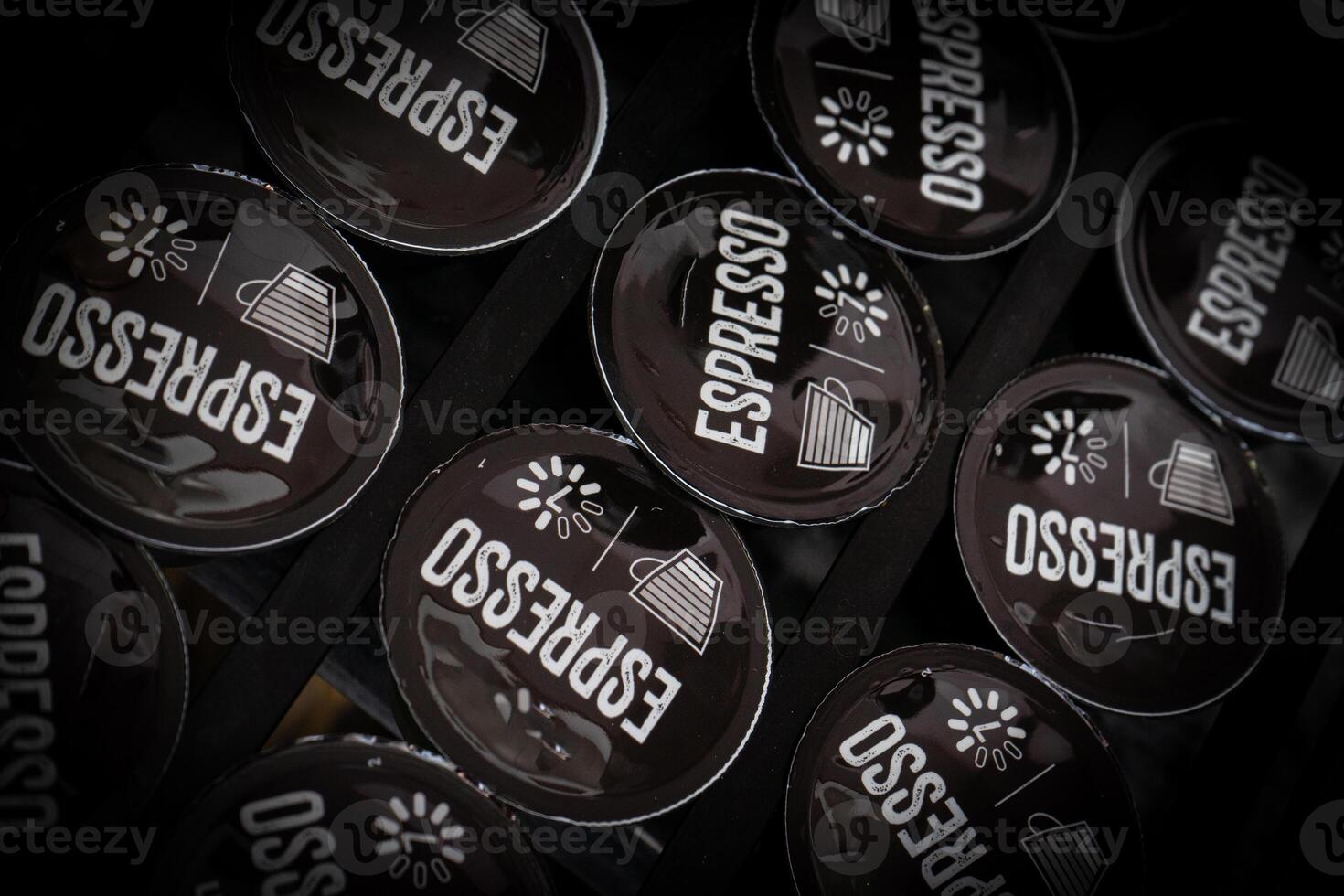 Row of dark coffee capsules neatly arranged in a sleek, modern coffee pod holder, creating a minimalist and elegant display photo