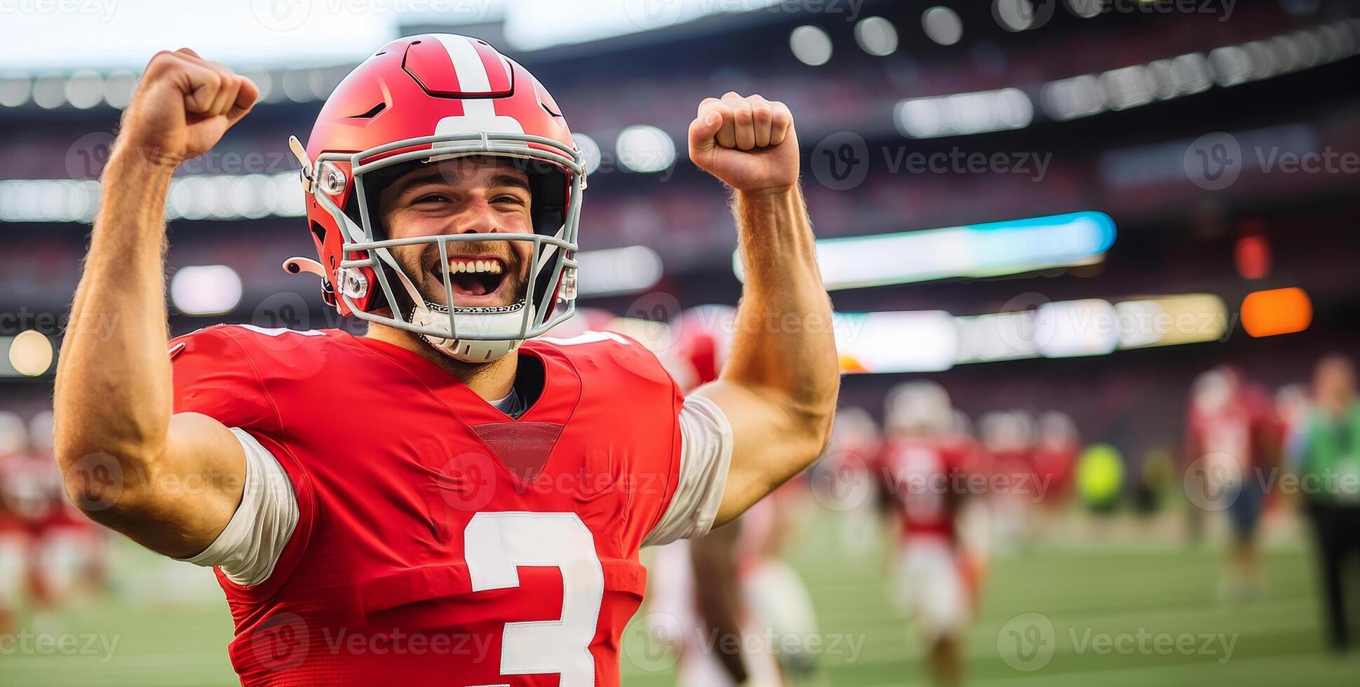 American football player in red uniform rejoices and raises his hands in fists up photo