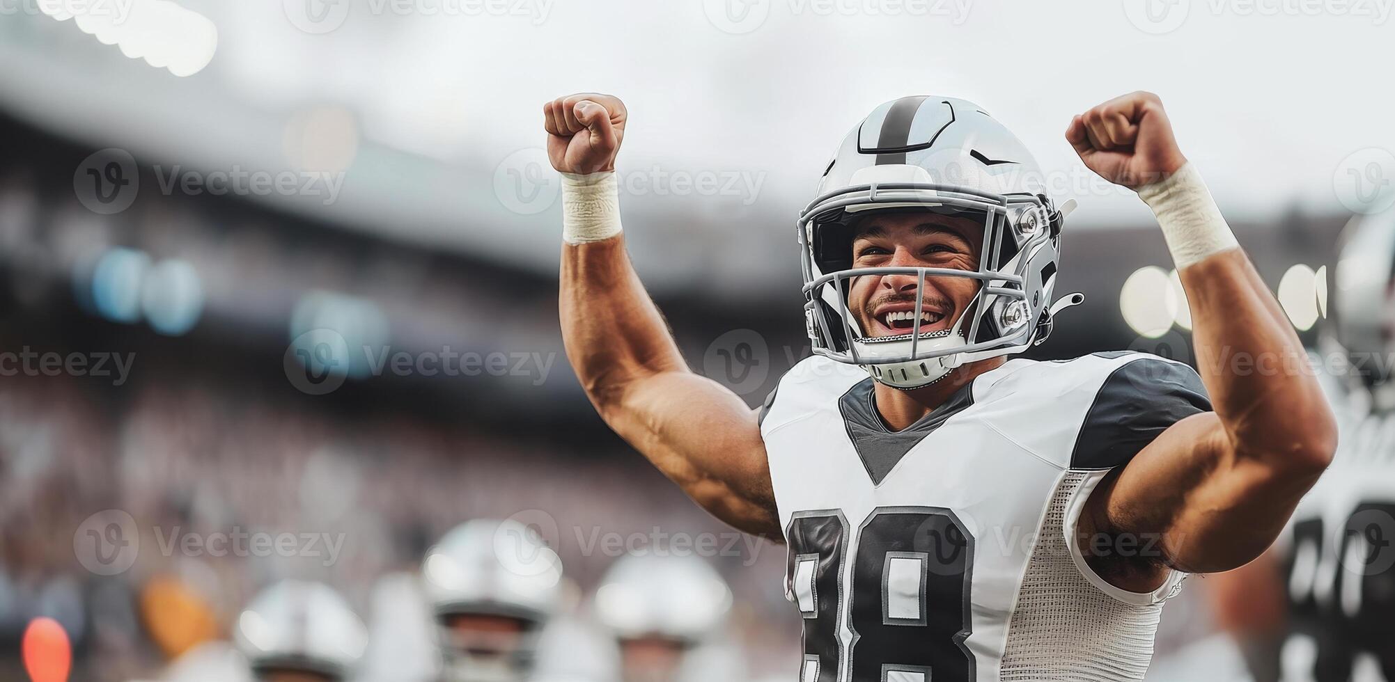American football player in black and white uniform cheers and raises his fists up photo