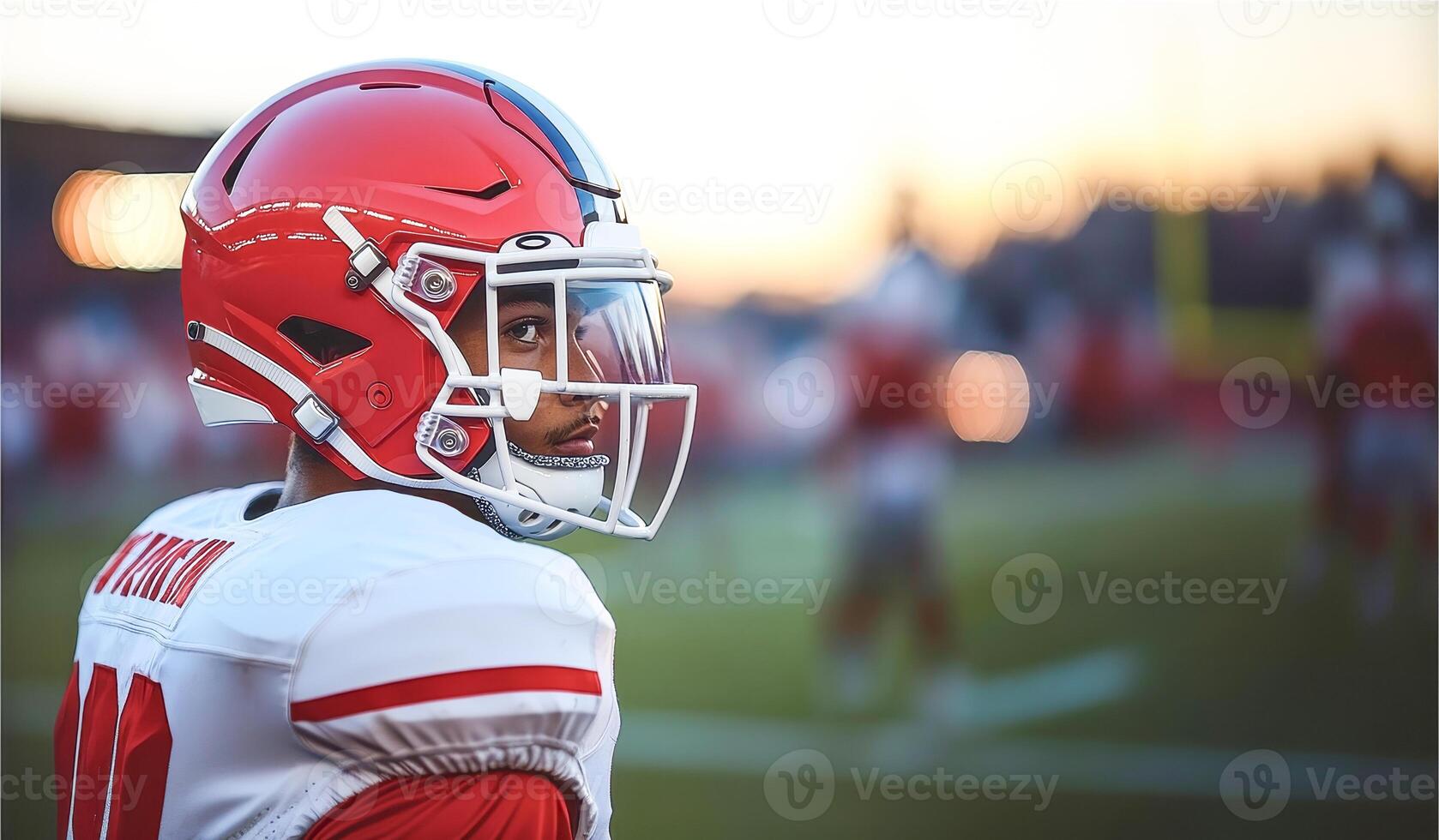 American football player in red and white uniform and helmet with glass stands sideways photo