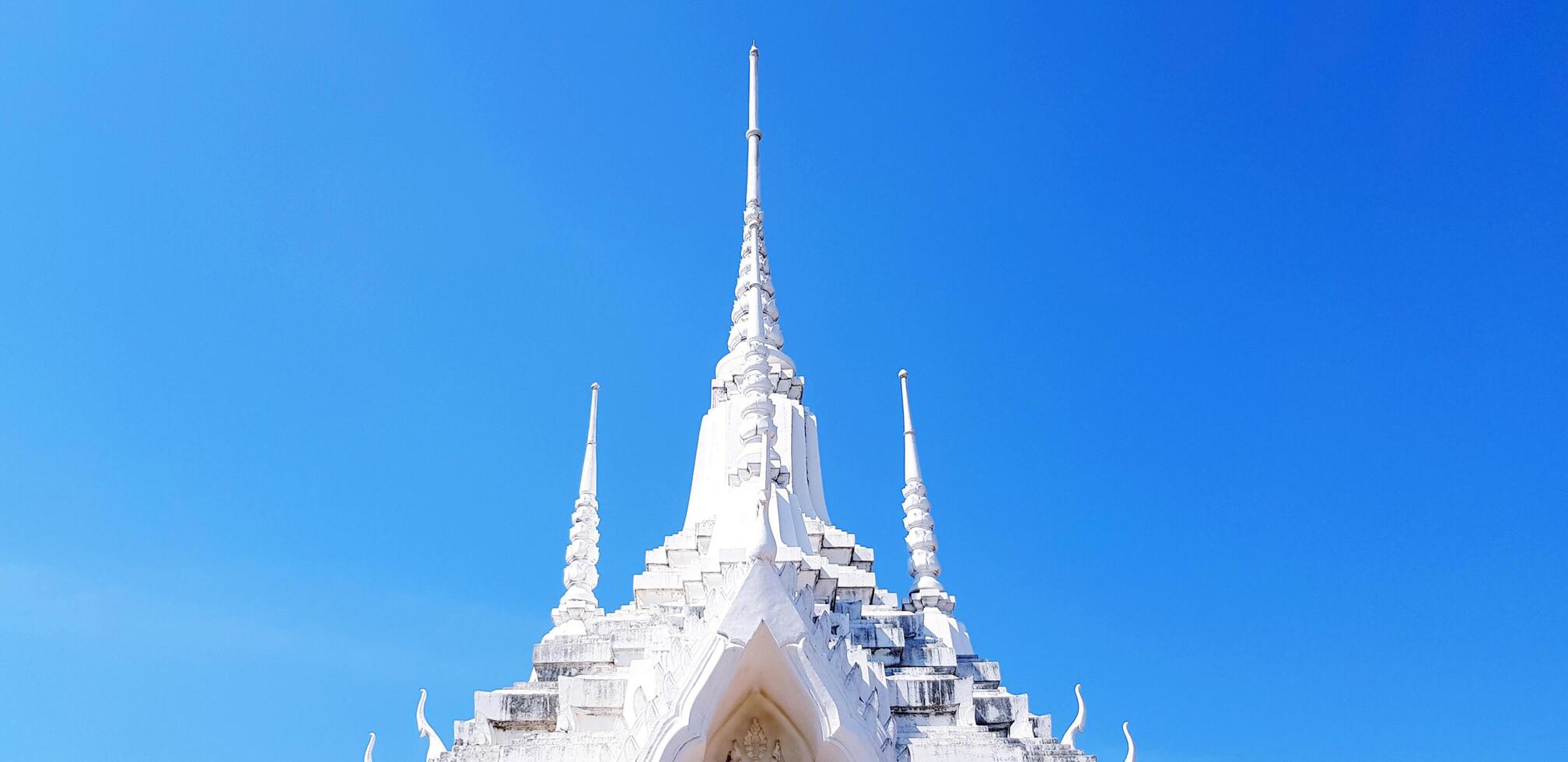 Beautiful White pinnacle, Stupa or pagoda with clear blue sky and copy space. Religion, Ancient temple, Exterior building and Buddhism concept. photo