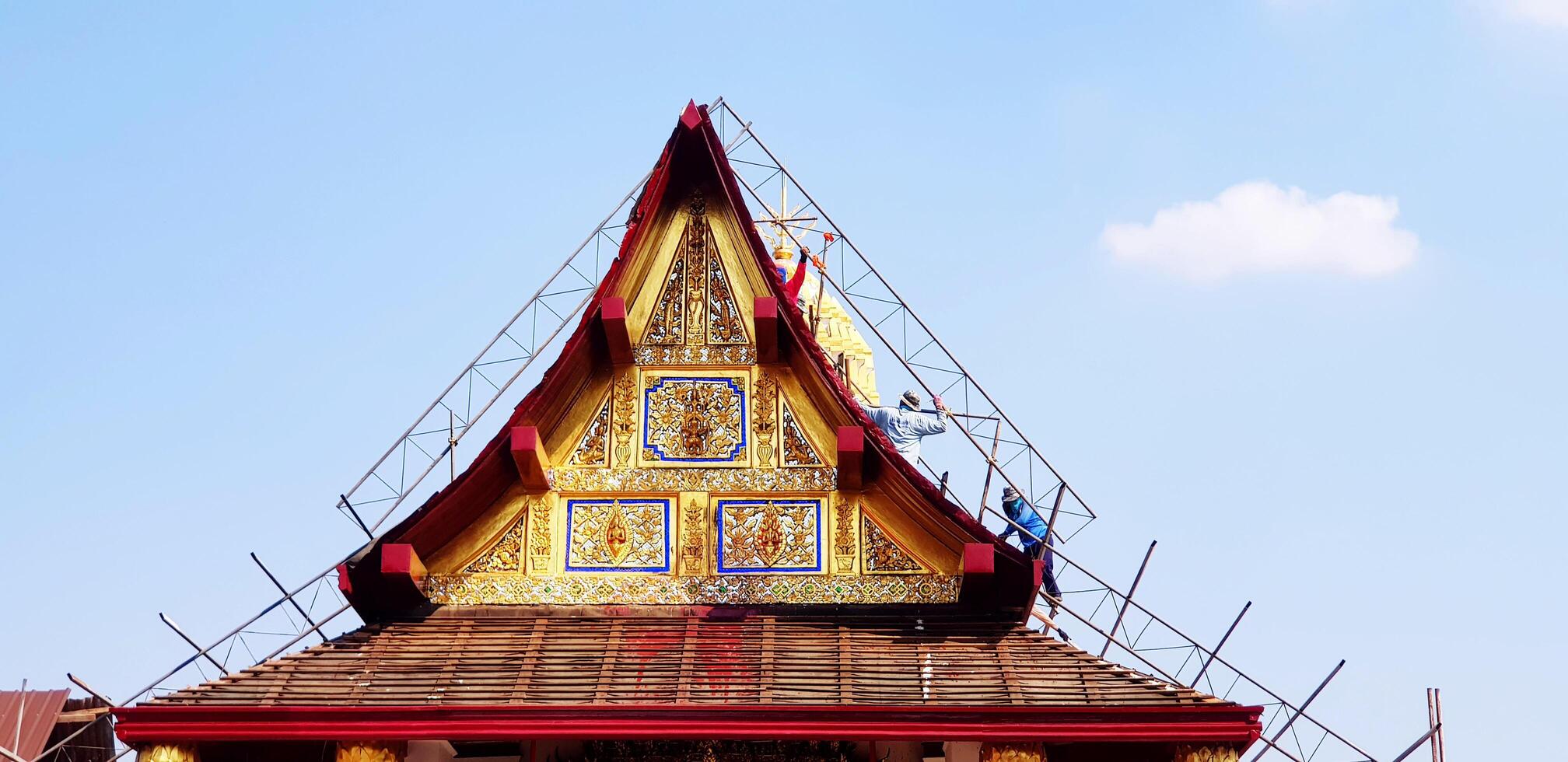 Construction workers repairing or fixing roof of ancient temple and clear blue sky background with copy space at Wat Phra Sri Rattana Mahatat Woramahawihan or Wat Yai temple in Phitsanulok, Thailand. photo