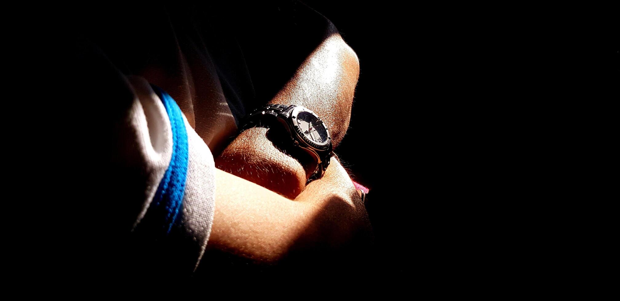 Close up hand crossing arms or fold ones arms and wearing watch with sunlight shining. Art, People, Object and About the time concept. photo