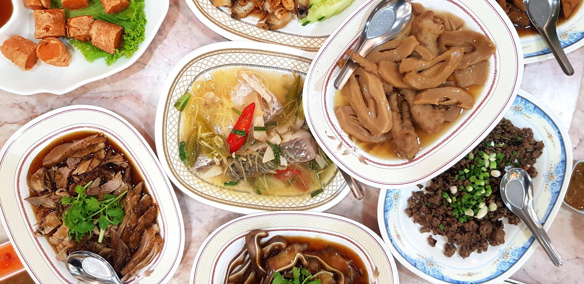 Flat lay of dinner food with boiled duck, Fish, Vegetable and fried minced pork on marble table at Thai local restaurant. Delicious, Top view object and Hungry concept. photo