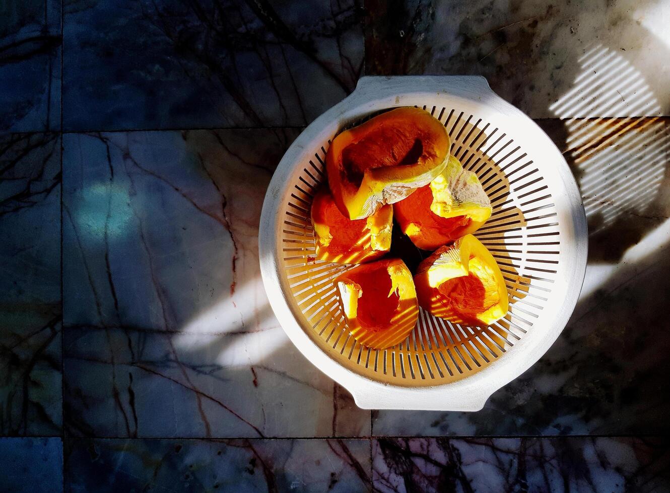 Top view slice of pumpkin in white basket on marble floor background. Fresh fruit or organic vegetable and healthy food with copy space and shade of light. photo