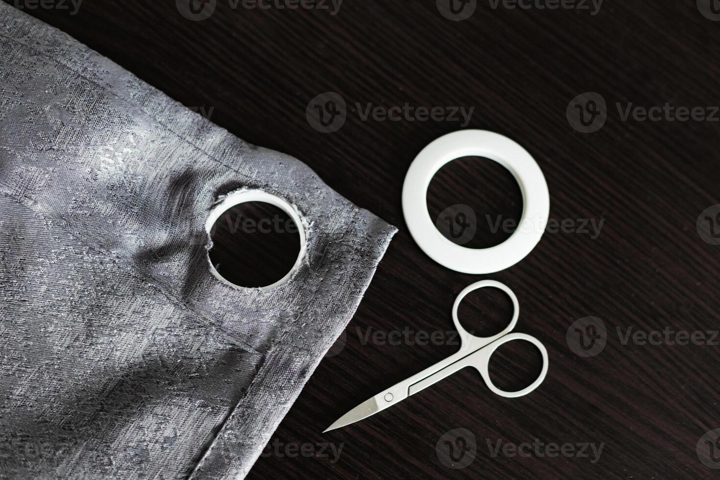 installing eyelets in curtain, cutting out a hole for the grommet with scissors photo