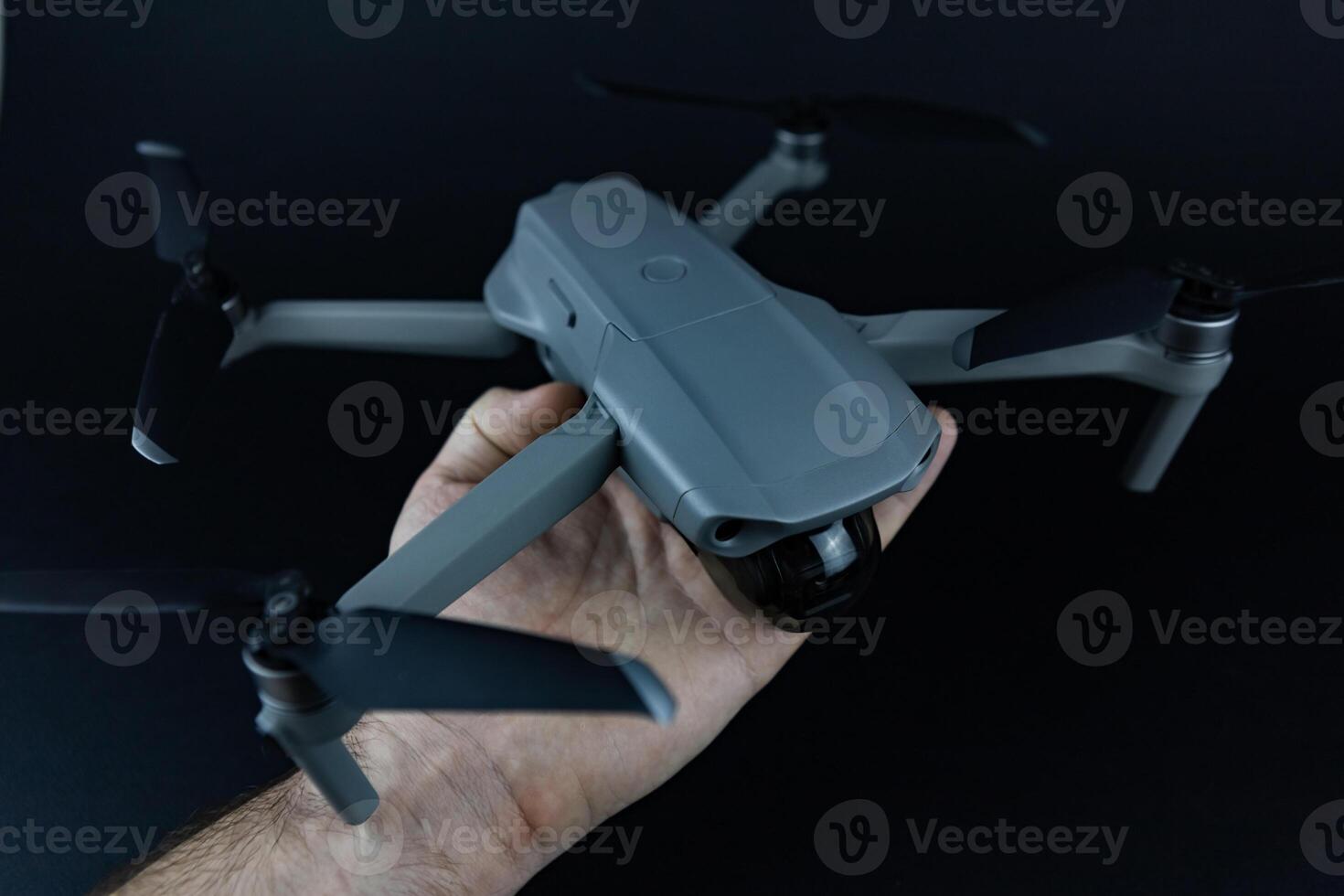 a man's hand holds a drone in his hands against the black background photo