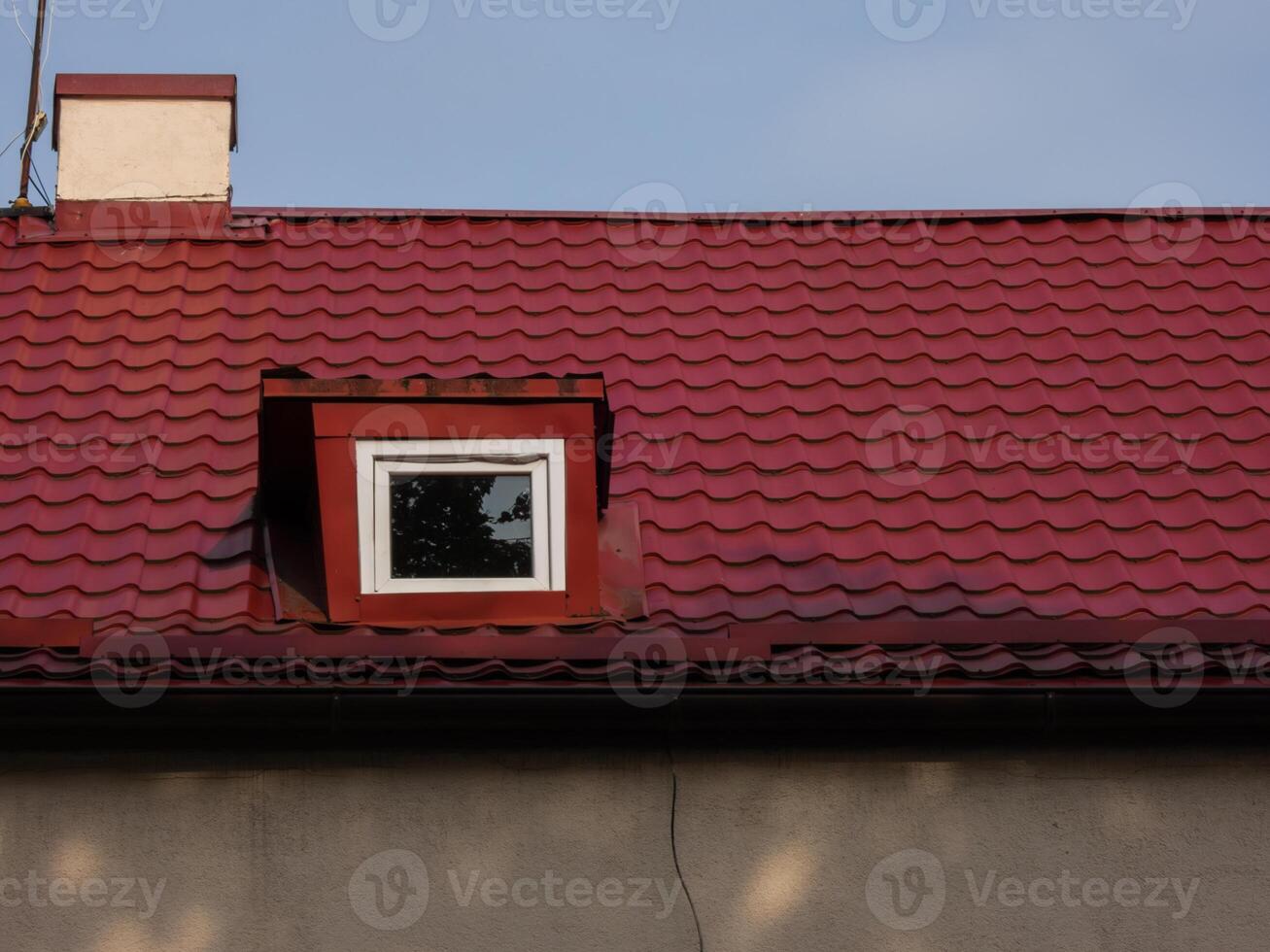 Roof of a house made of red tiles with a chimney and attic photo
