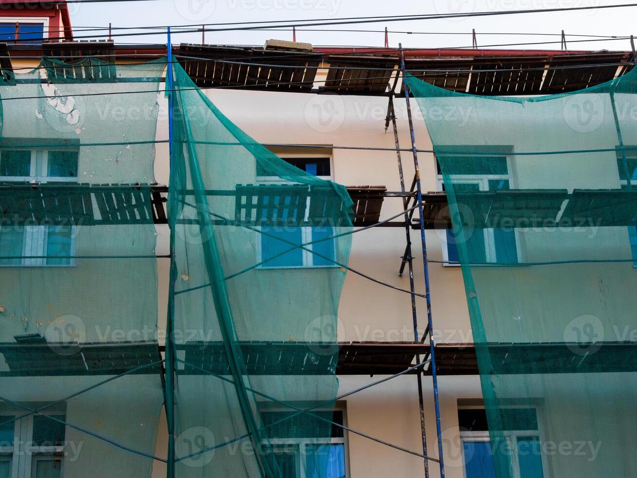 Scaffolding with protective mesh on building, facade restoration photo