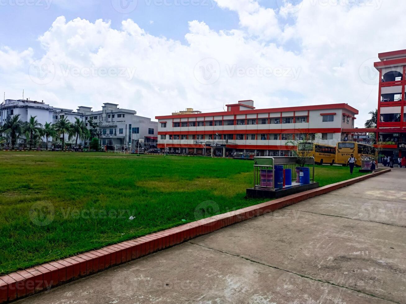 New School Building with Hard Lines and Bright Orange and White Detail and there is a big grass field Infront of the School building photo