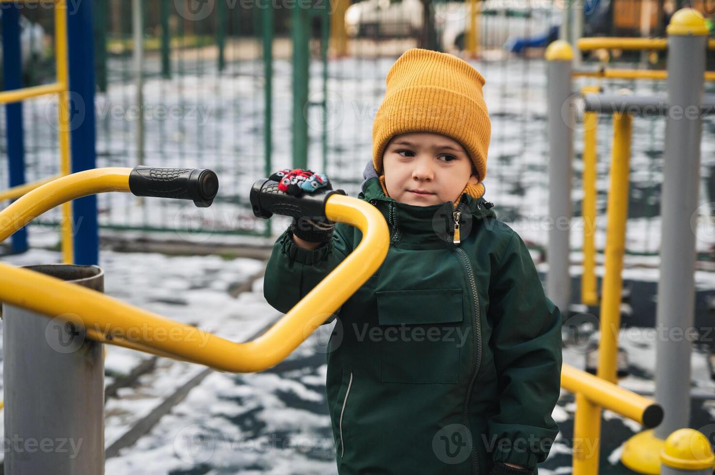 Sad lonely child kid boy playing on playground alone in park in winter photo
