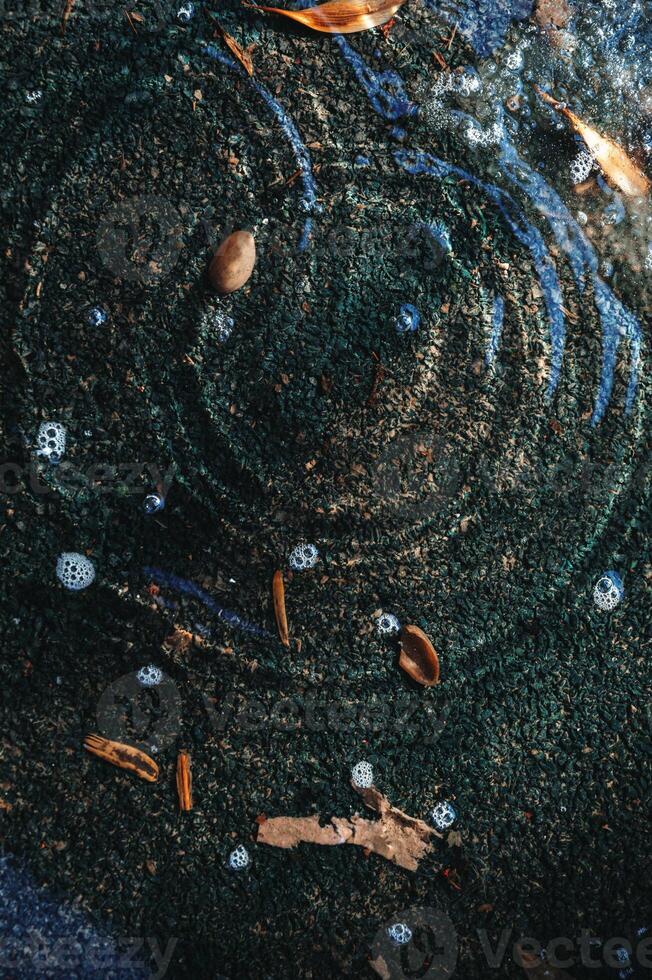 puddle on asphalt with drops of spring raindrops and circles on water photo