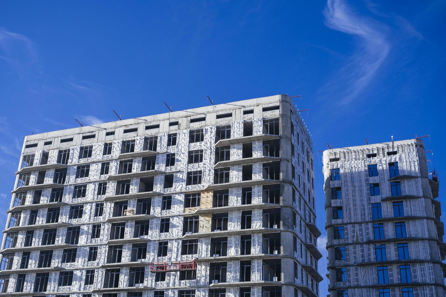 SHYMKENT, KAZAKHSAN - JANUARY 03, 2024. residential building under construction with installed thermal insulation panels on the facade against blue sky background photo