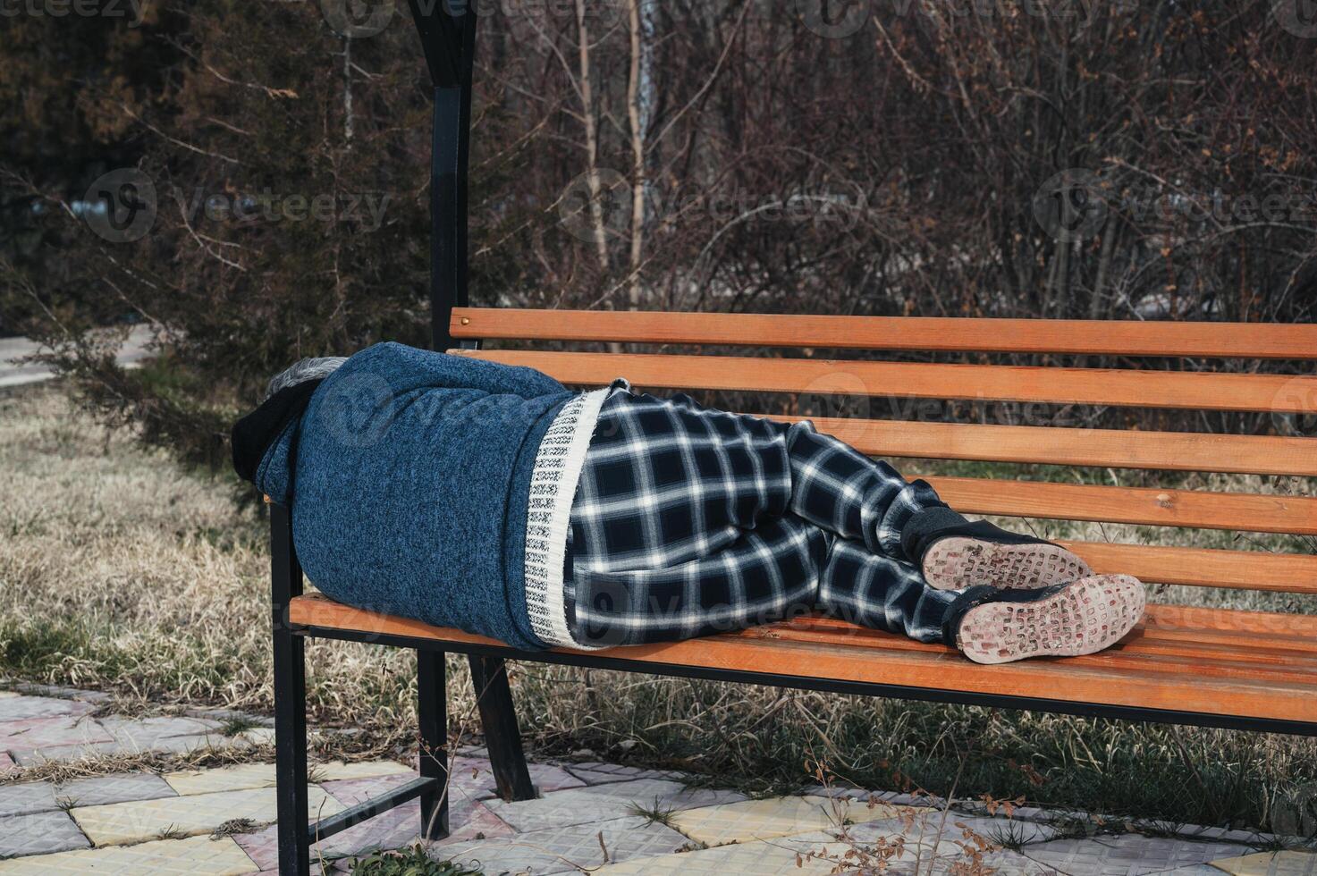 homeless elderly old man lies sleeping on park bench in autumn photo