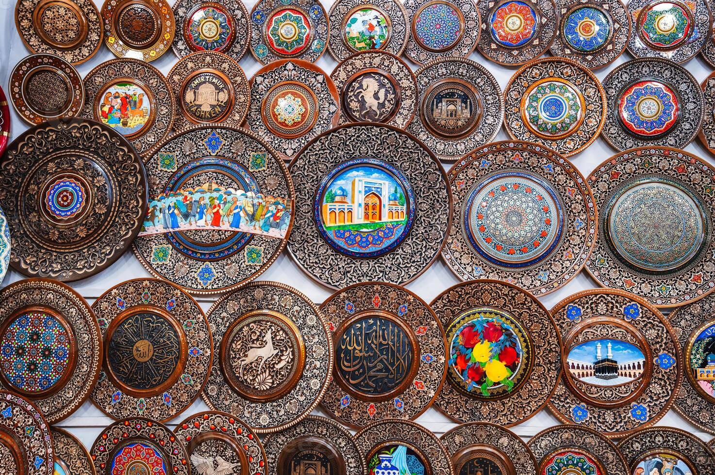 Uzbek wooden handmade gift plates with wood carvings hand-painted in souvenir shop of Uzbekistan photo