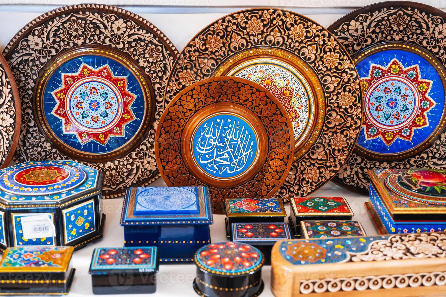 handmade Uzbek wooden gift plates and caskets with wood carvings hand-painted oriental patterns in the souvenir store in Uzbekistan photo