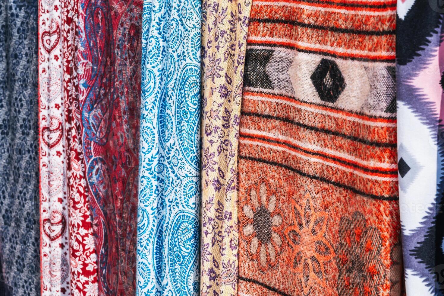 Traditional silk Indian scarves with bright colorful pattern at an Asian bazaar close-up photo