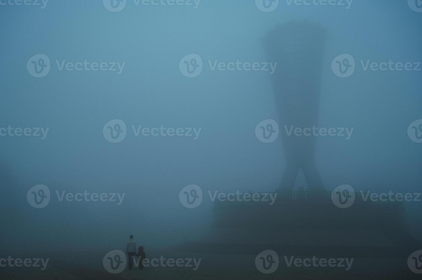backs of mother woman with child son walking in a misty foggy mystical park in evening. A misty landscape with people in autumn in a misty fog mist haze photo