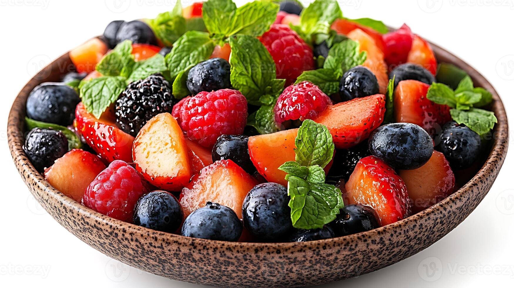 A bowl of fresh fruit salad with strawberries, blueberries, raspberries, blackberries, and mint leaves. photo