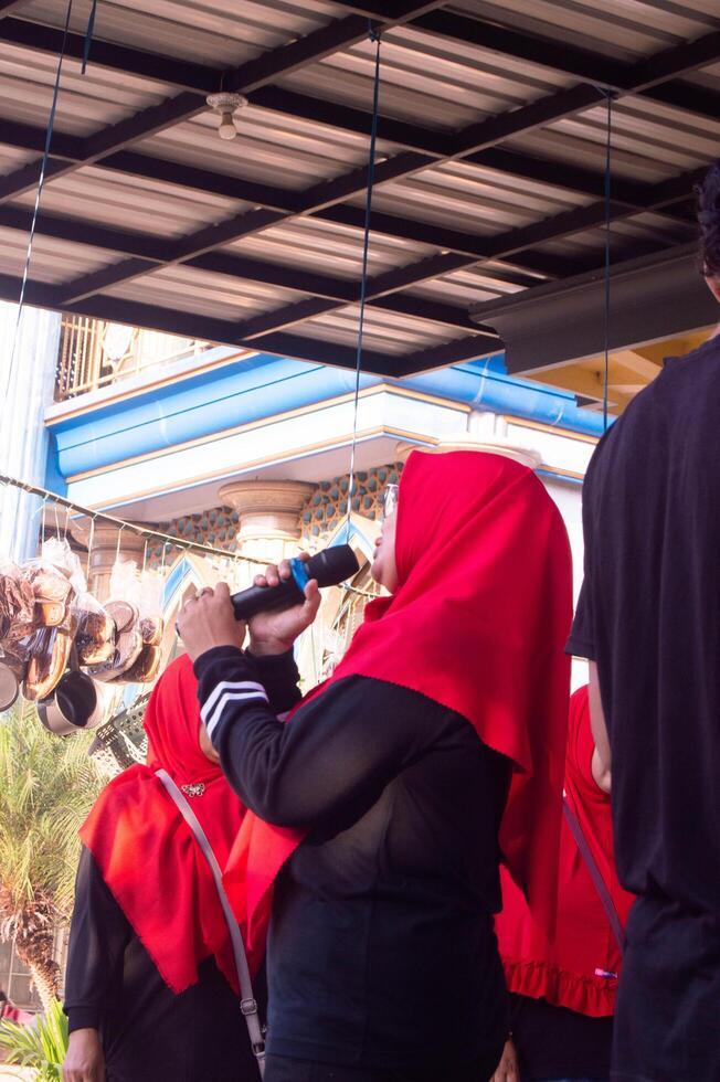 gresik, indonesia, 20 august 2023 - shot on indonesian muslim woman talking into microphone photo