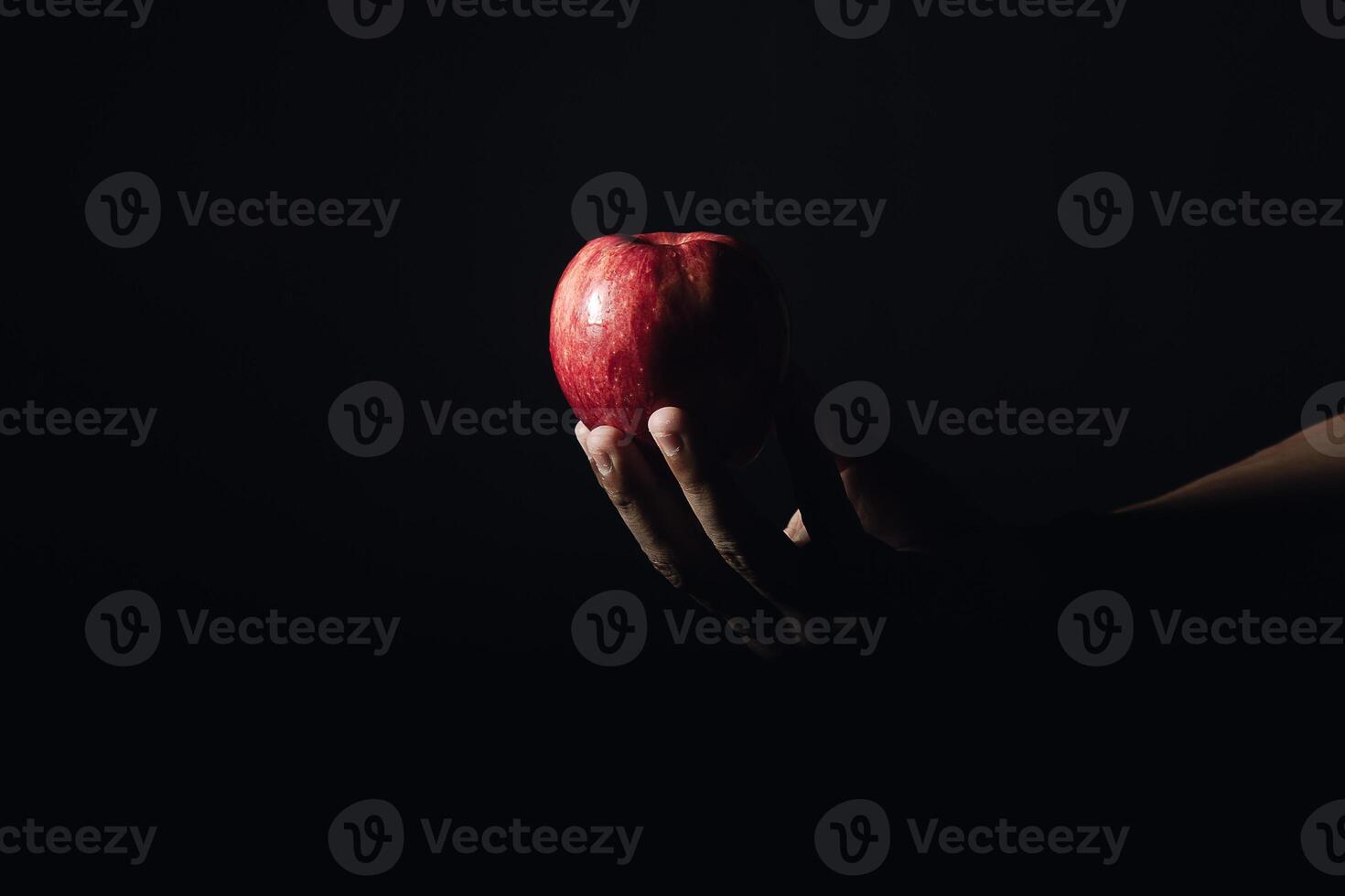 hand holding an apple in the dark photo