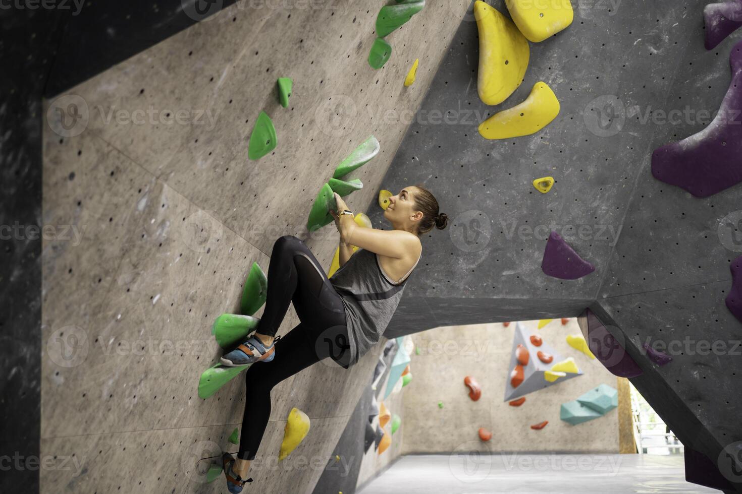 Determined woman climbing artificial wall in gym photo