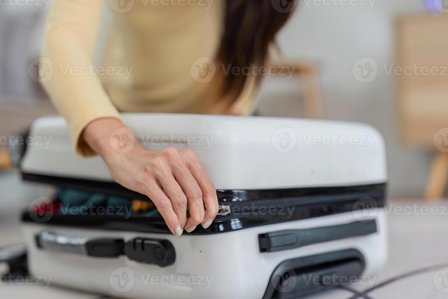 Young Woman Packing a Suitcase for Travel at Home, Preparing for a Vacation or Business Trip, Close-Up of Hands Zipping Luggage photo