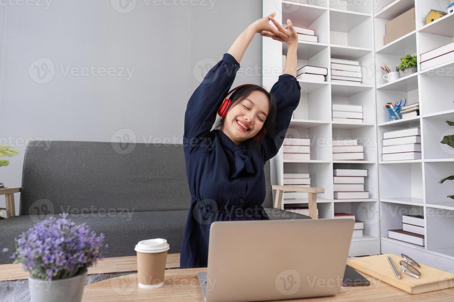 Relaxed Young Woman Enjoying Social Media on Laptop at Home with Headphones, Coffee, and Modern Decor photo