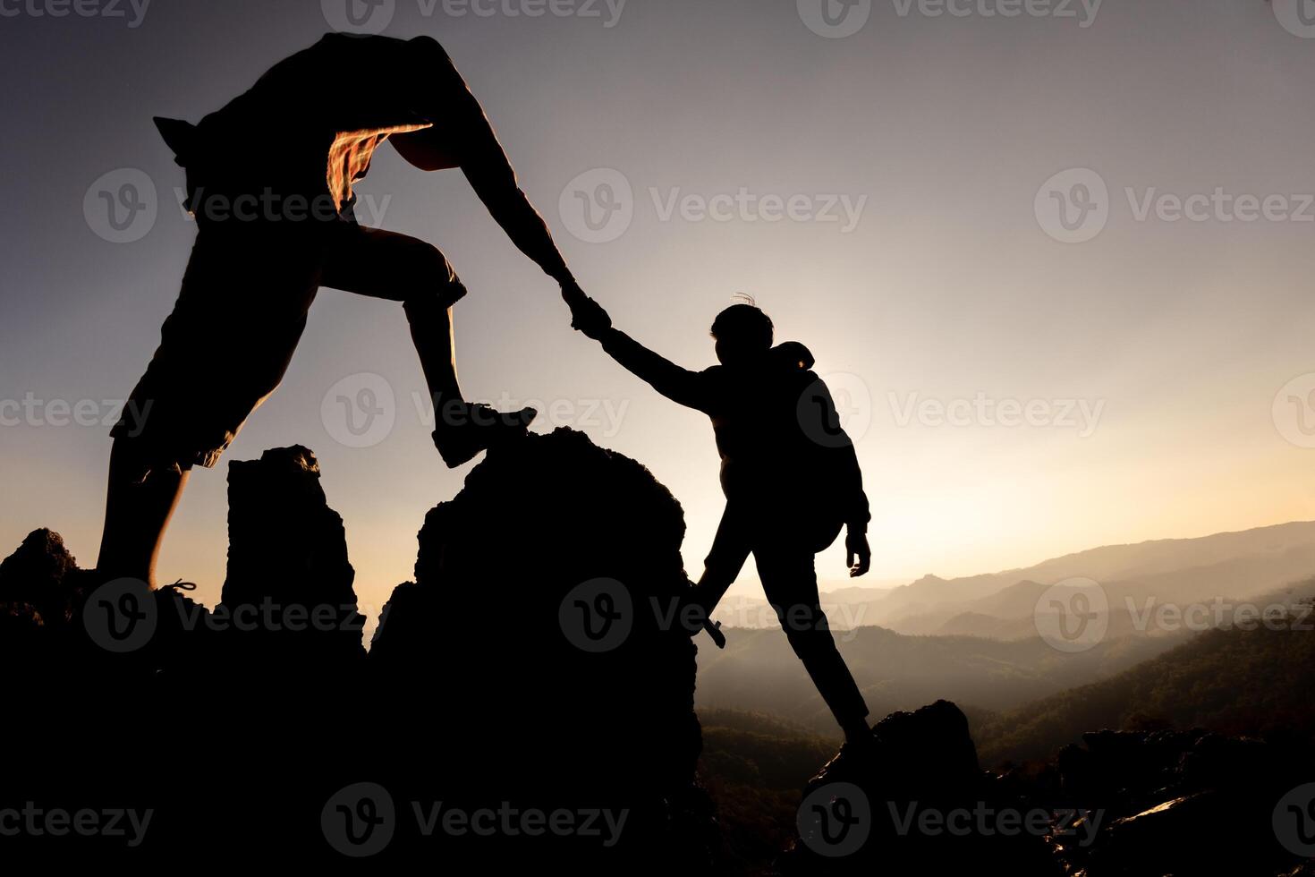 Silhouette of hiker helping each other hike up a mountain at sunset. People helping and, team work concept. photo
