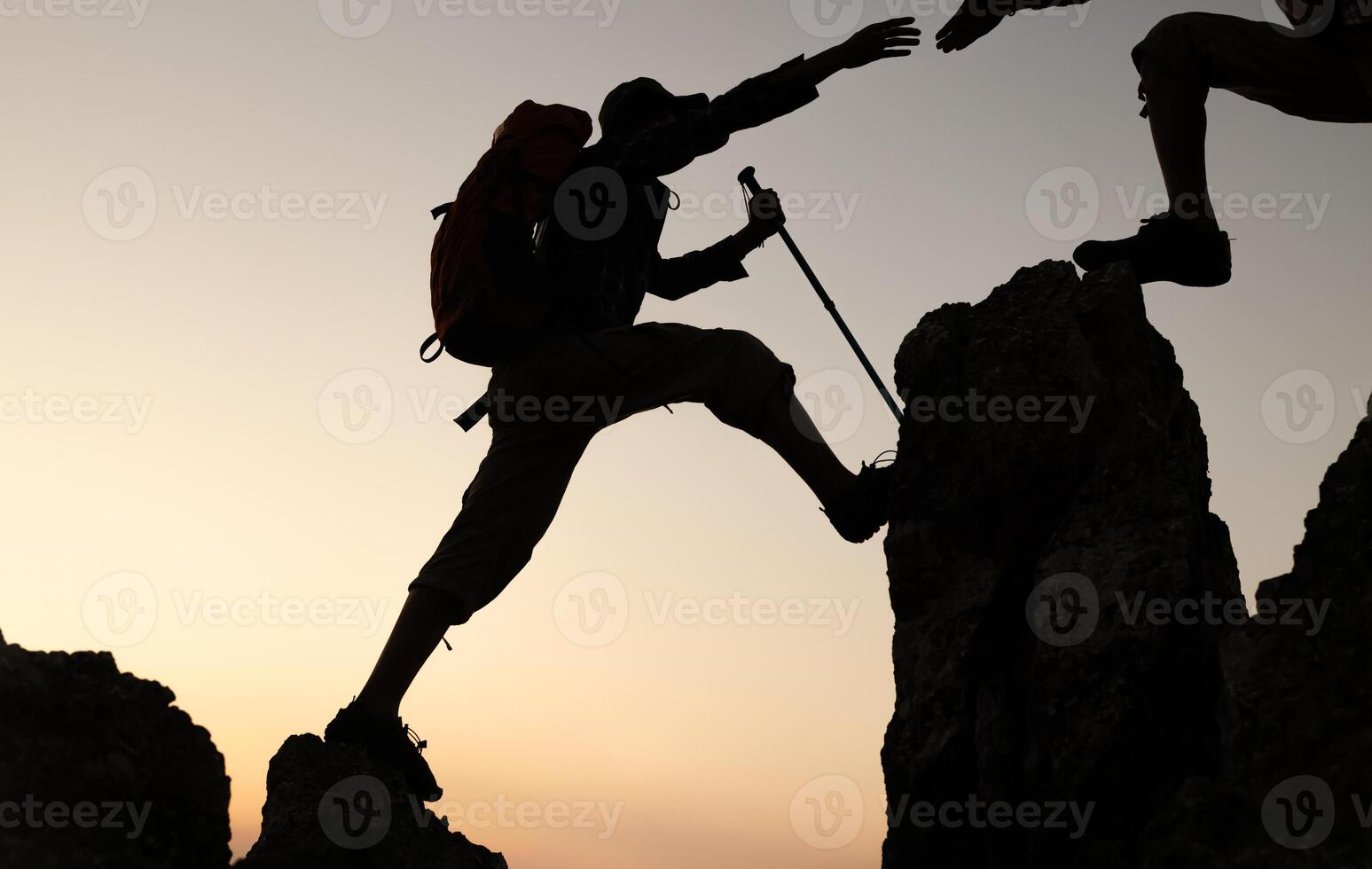 Silhouette of hiker helping each other hike up a mountain at sunset. People helping and, team work concept. photo