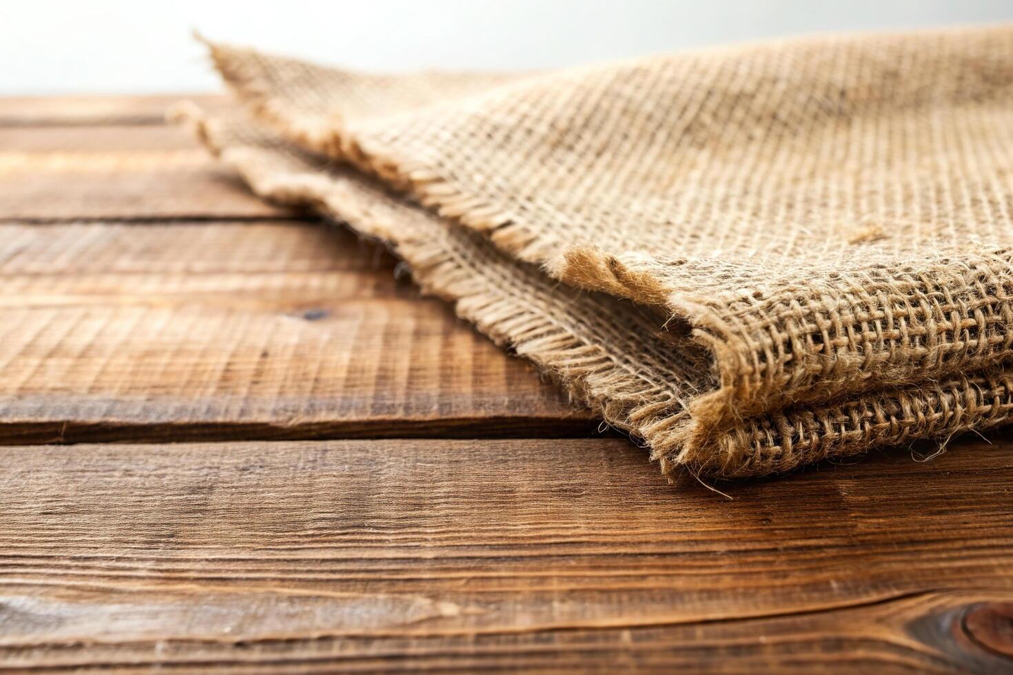 The stock photo features a close up view of the rough and textured burlap fabric placed on a wooden table with a white background creating a forced perspective effect, pattern