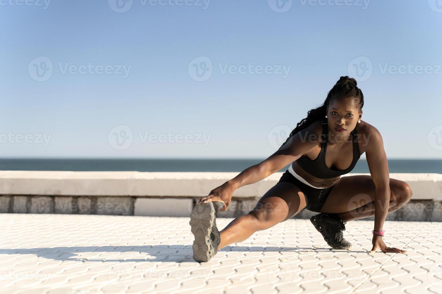 Healthy woman training and doing stretching before exercise on the beach photo