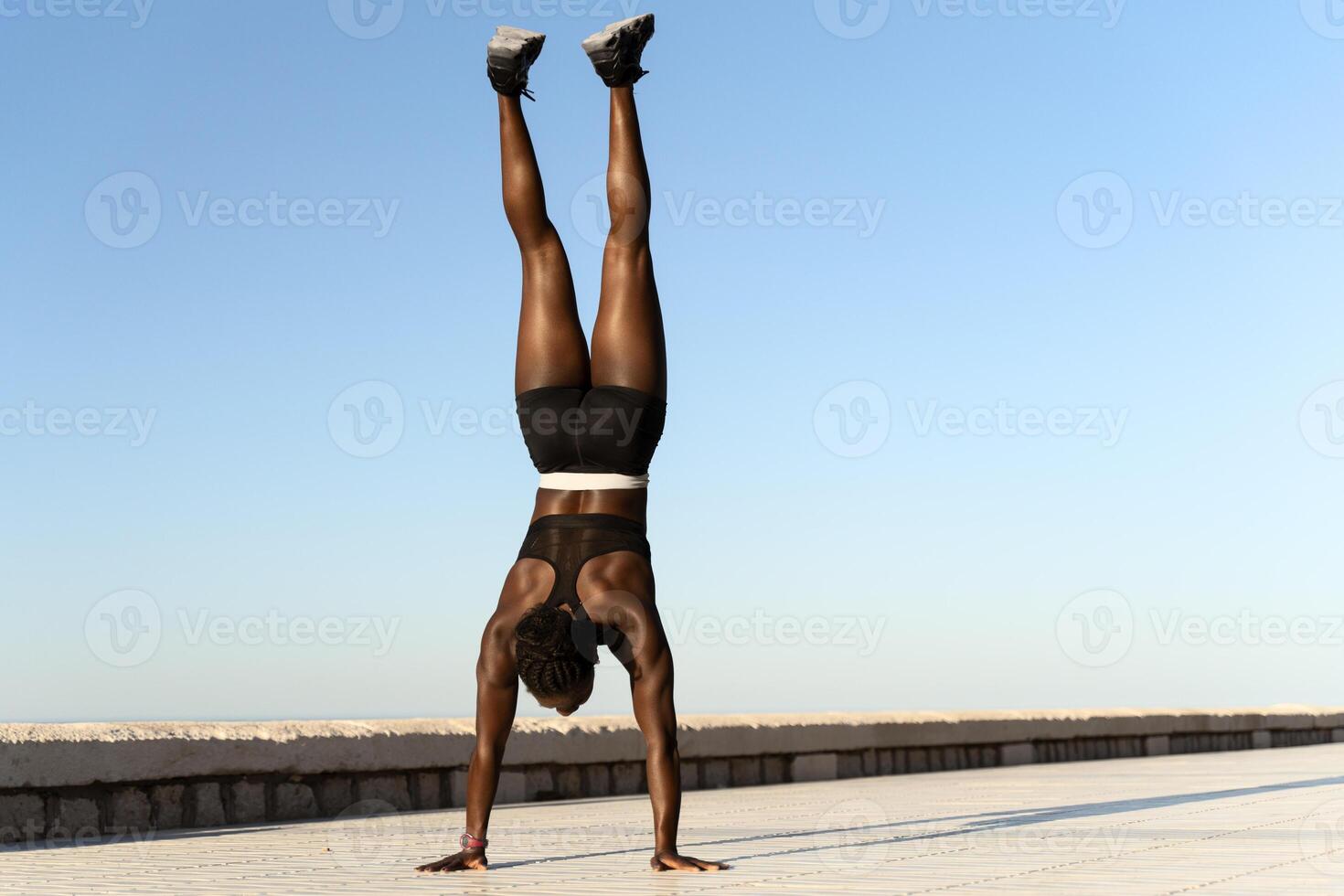 Strong woman in sportswear standing on hands for training body balance photo