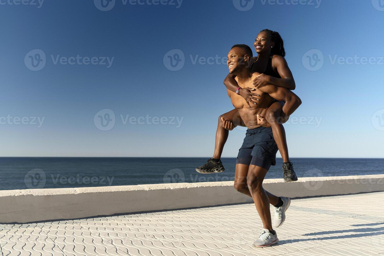 Sport lover piggyback riding on summer beach, spending time together after morning workout photo