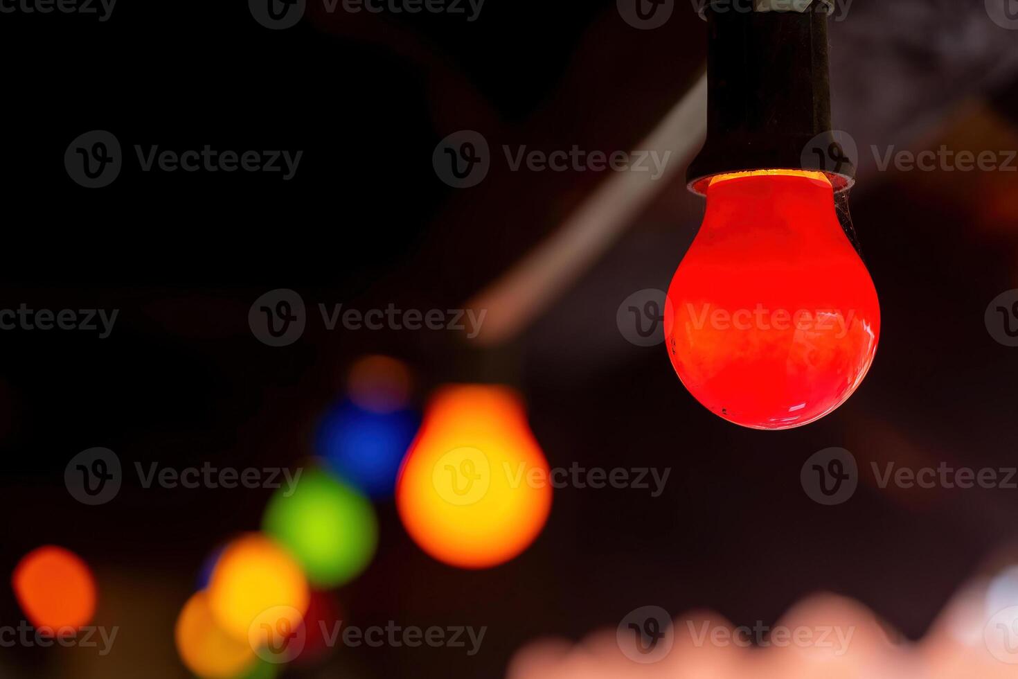 red light bulb is the center of a colorful string of lights photo