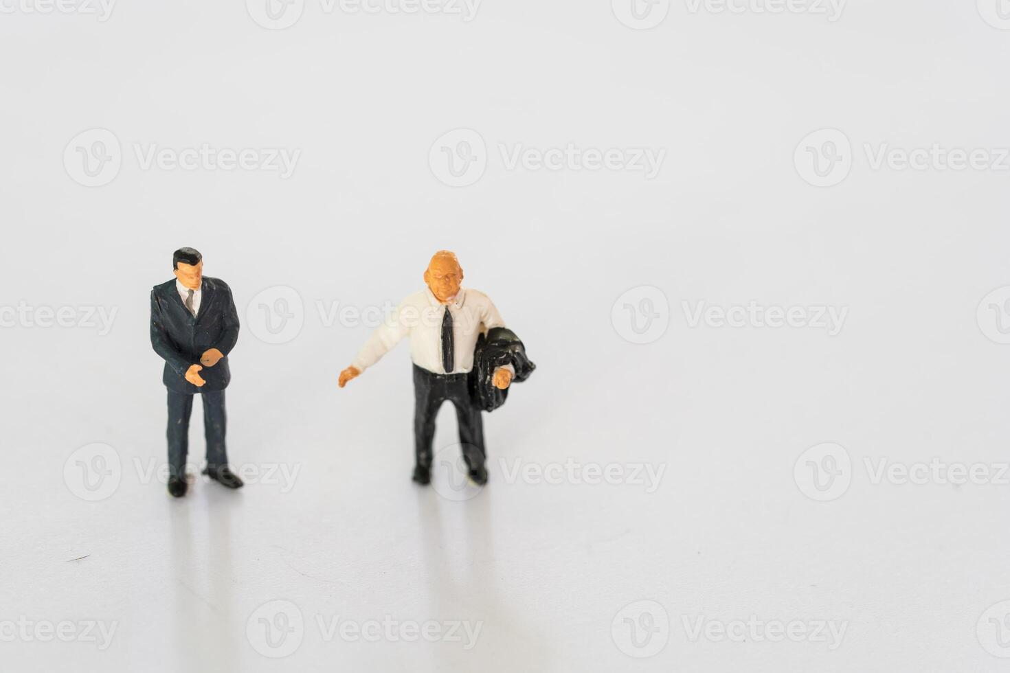 Miniature businessmen stand on white background together photo