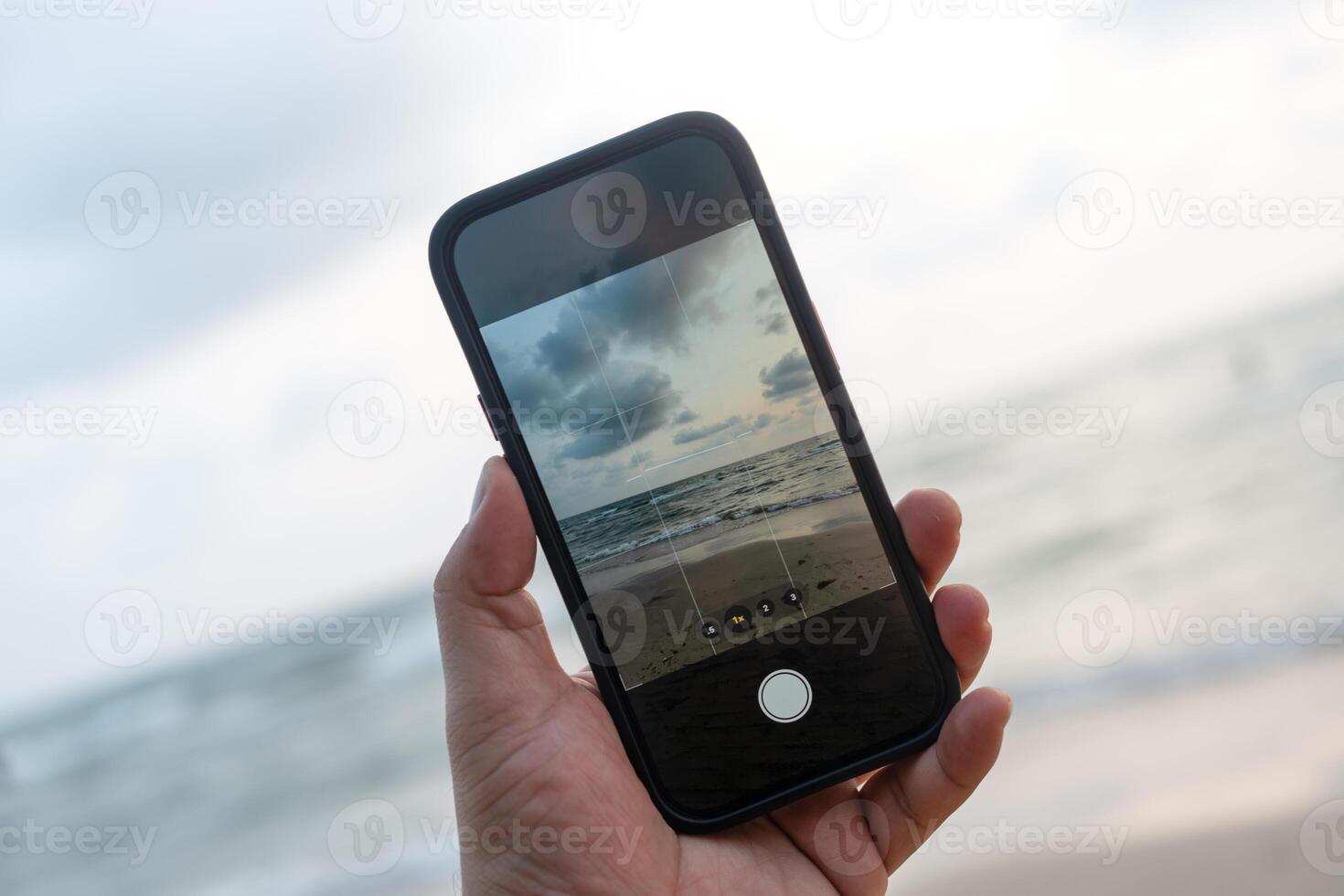 Man taking a photo with the mobile phone on the beach during sunset