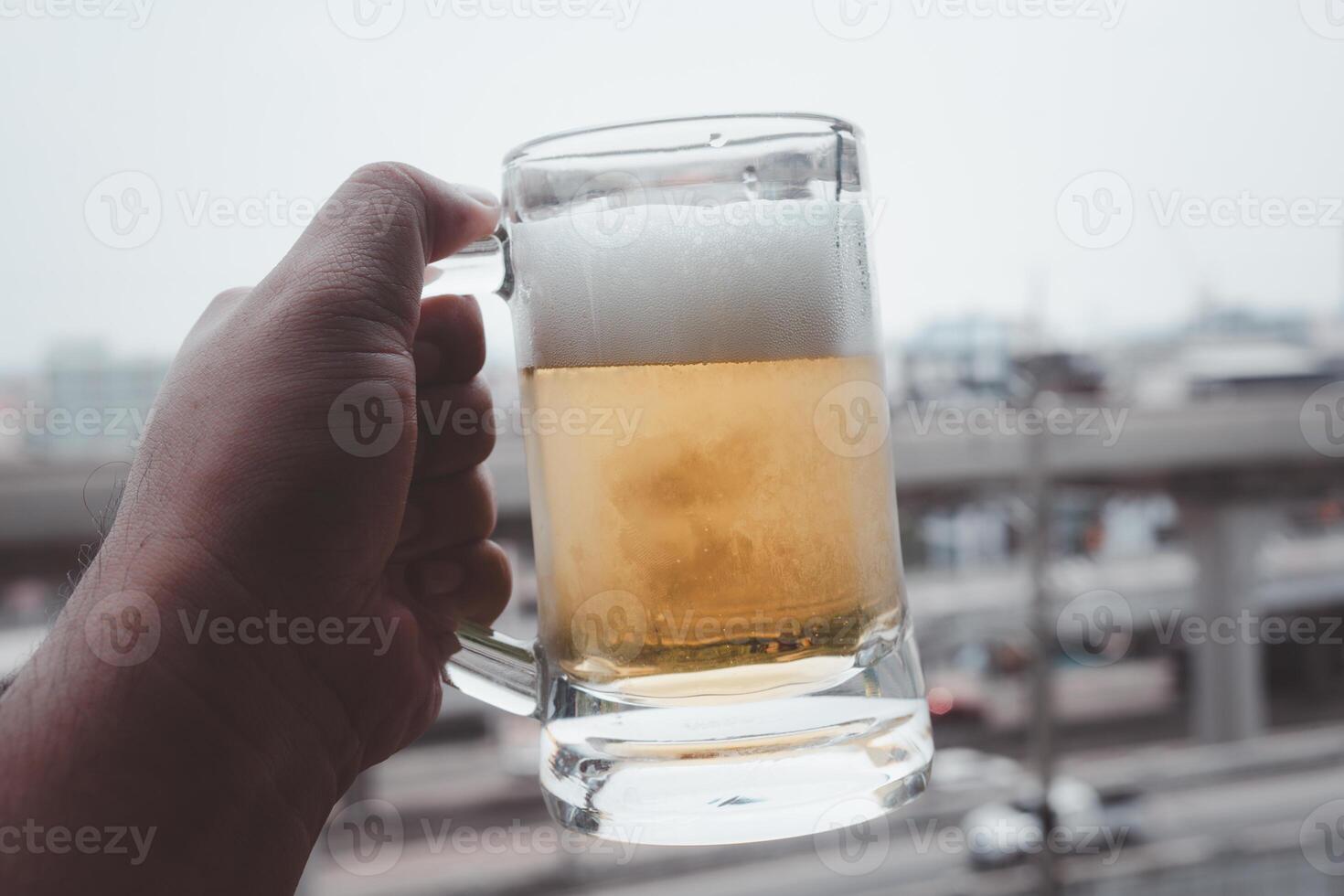 Holding a beer cup with foam on top in the condominium on a sunny day photo