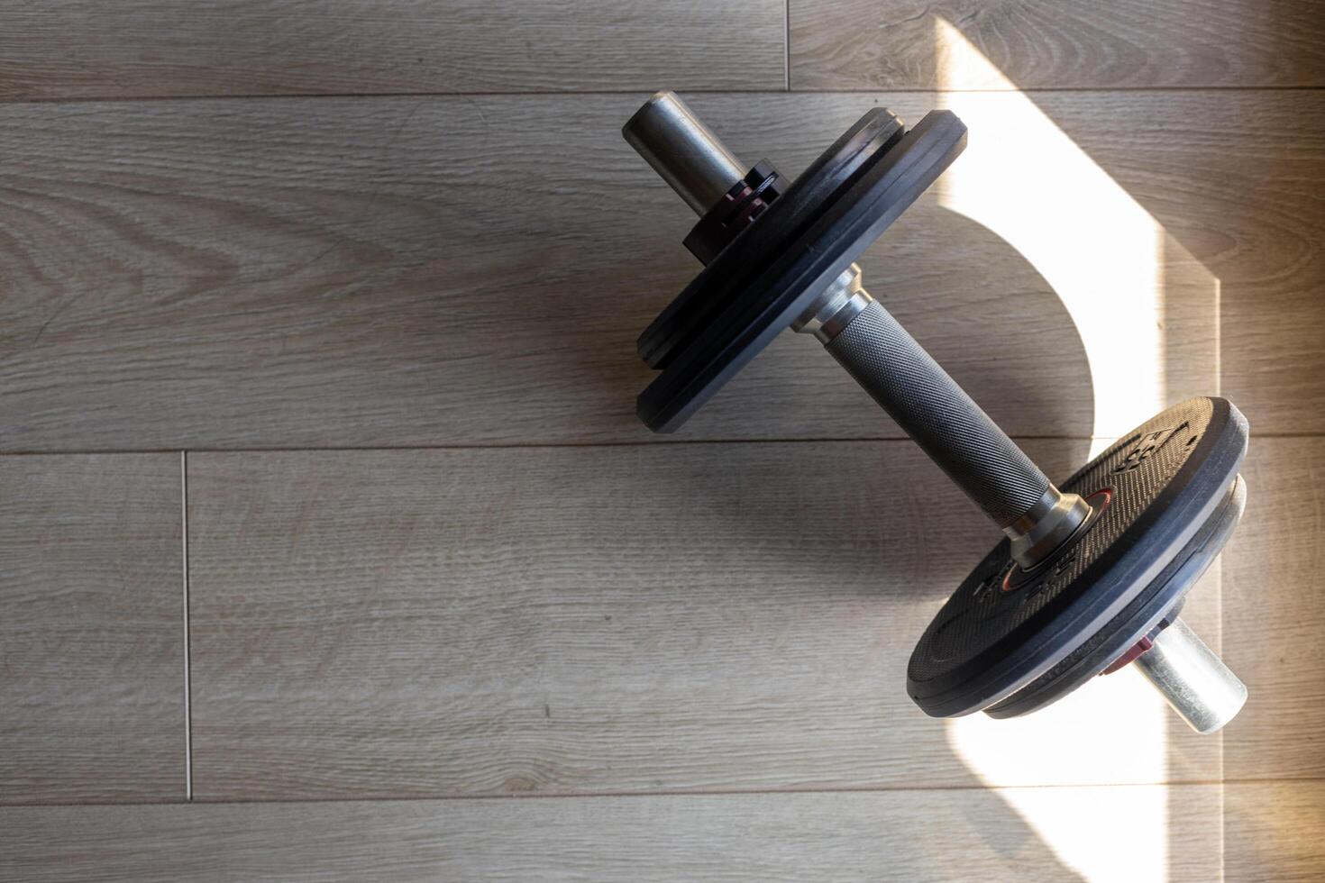 Dumbbell on Wooden Floor with Shadows photo