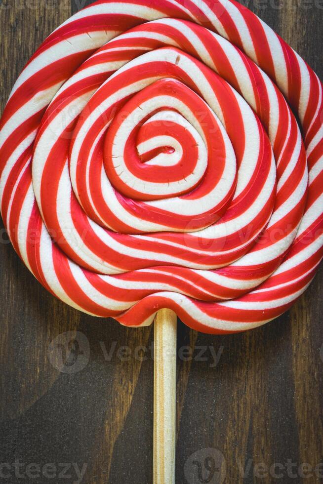 Close up from a Christmas lollypop on a wooden background. Red and white swirl. Background for Christmas. photo