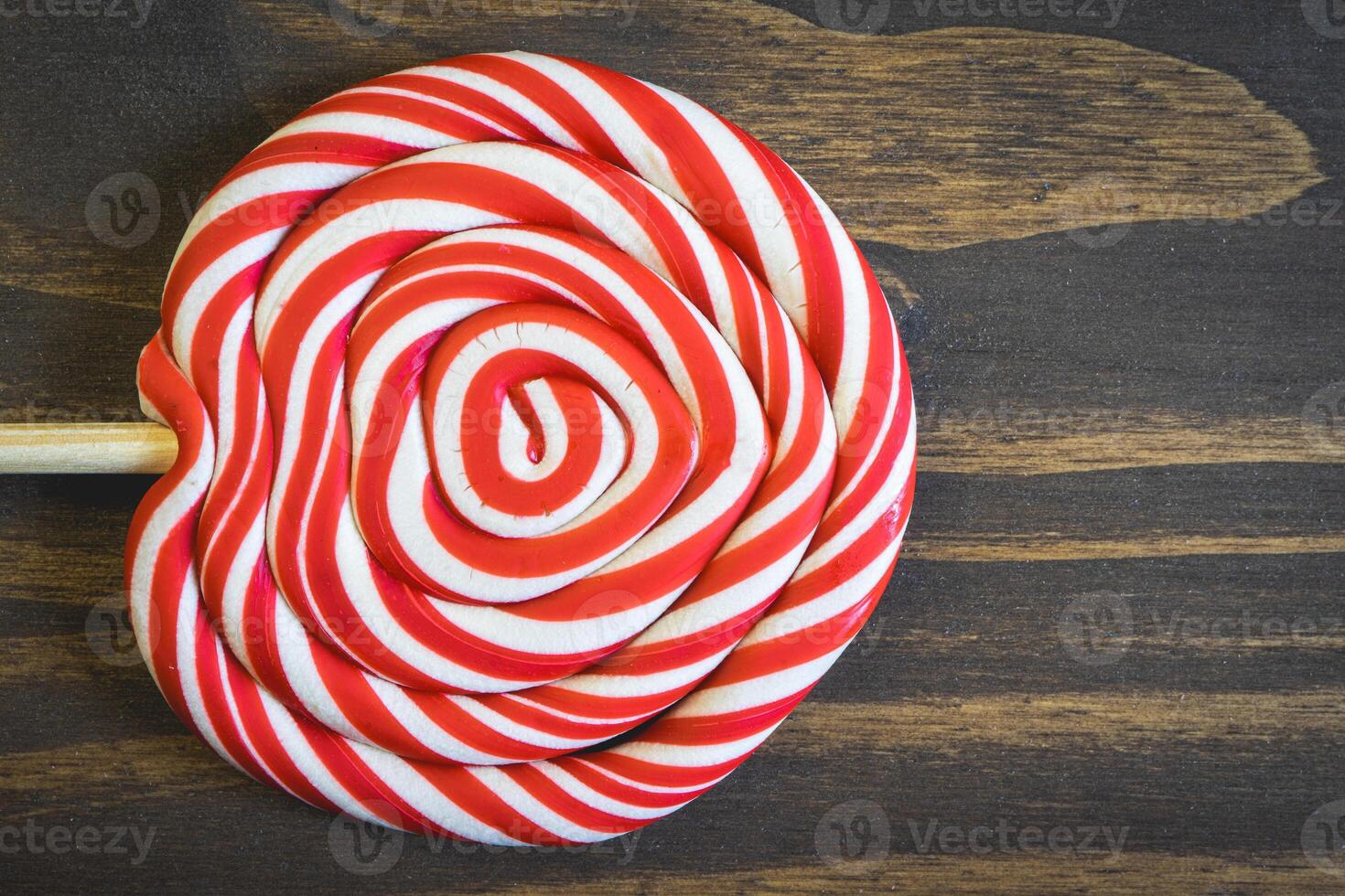 Close up from a Christmas lollypop on a wooden background. Red and white swirl. Background for Christmas. photo