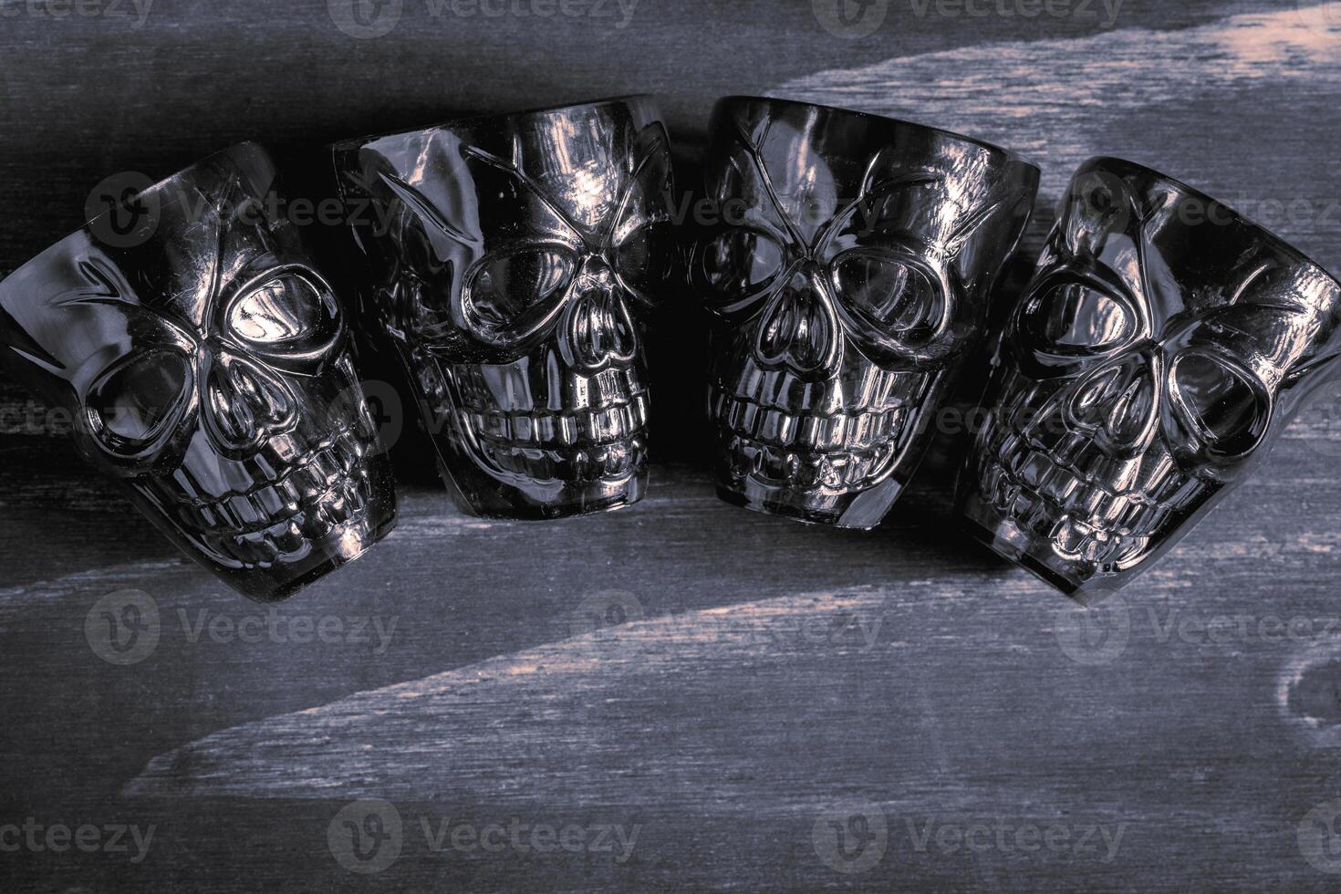 A couple of shot glasses in the shape of a skull, for a Halloween Party. On a wooden background, in black and white. photo
