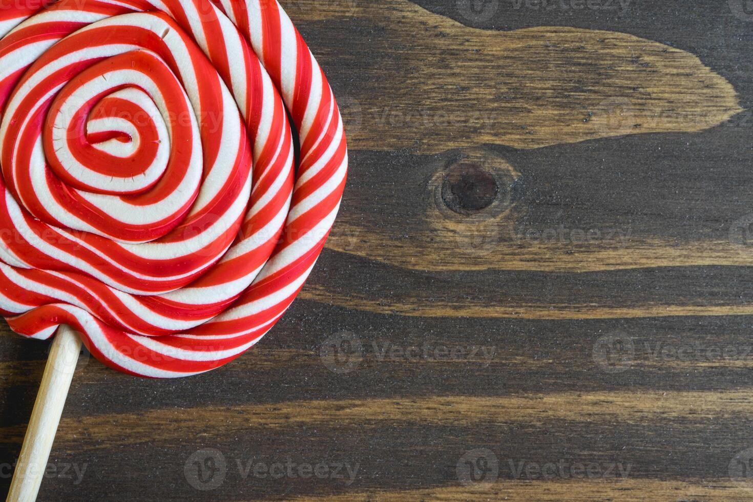 Close up from a Christmas lollypop on a wooden background. Red and white swirl. Background for Christmas. photo