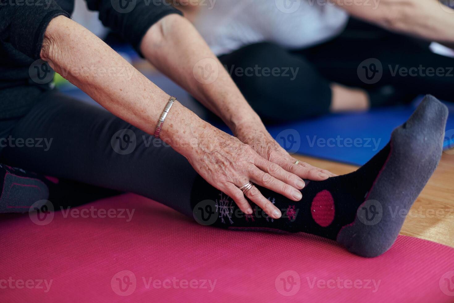 A group of senior women engage in various yoga exercises, including neck, back, and leg stretches, under the guidance of a trainer in a sunlit space, promoting well-being and harmony photo