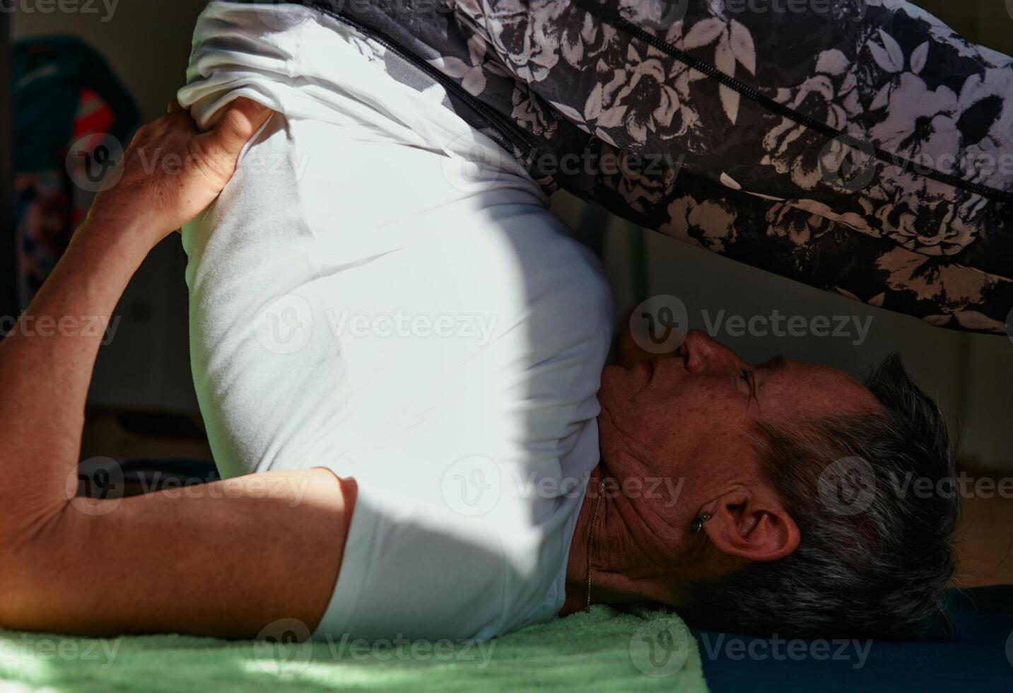 Senior Woman Practicing Back Stretches in a Sunlit Space for Optimal Health and Well Being photo