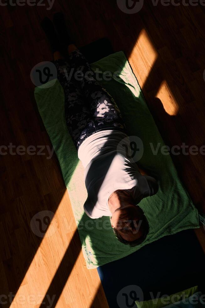Senior woman practicing stretching and meditation on the floor, focusing on proper alignment and relaxation. photo
