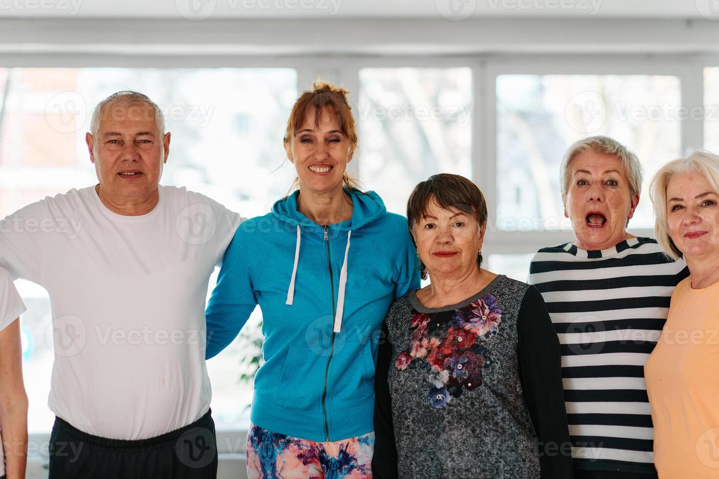 A group of seniors and one man happily pose with their yoga instructor after a successful training session. photo